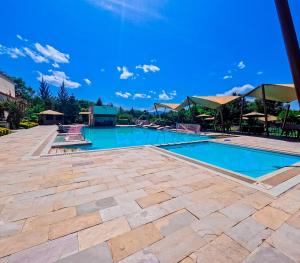a swimming pool in a resort with a blue sky at Githima Cottage 10 at Swara Ranch in Nanyuki