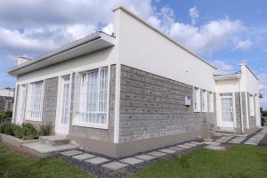 a house with white windows on the side of it at Githima Cottage 10 at Swara Ranch in Nanyuki