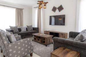 a living room with couches and a tv at Githima Cottage 10 at Swara Ranch in Nanyuki