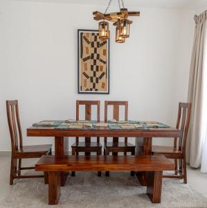 a dining room table with four chairs and a chandelier at Githima Cottage 10 at Swara Ranch in Nanyuki