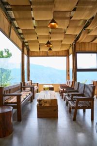 a room with chairs and a table and windows at Phỏng Lài Mountain Homestay - Ta Xua Peak View in Bắc Yên