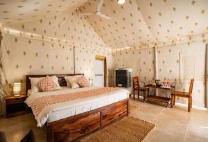 a bedroom with a large bed and a desk and a table at Yatra Desert Camp & Resort in Jaisalmer