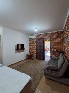 a living room with a couch and a brick wall at Espaço Gozzoli, Cantinho da Nonna in Espirito Santo Do Pinhal