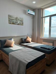 two beds sitting in a room with a window at Caspian Deluxe Apart Hotel in Aktau