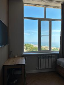 a room with three windows and a desk and a table at Caspian Deluxe Apart Hotel in Aktau