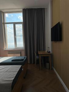 a hotel room with a bed and a desk and a window at Caspian Deluxe Apart Hotel in Aktau