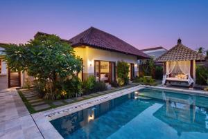 a villa with a swimming pool in front of a house at Lapiz Lazuli in Seminyak