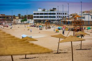 a beach with many straw umbrellas and people on it at Résidence Acharif in Tan-Tan Plage