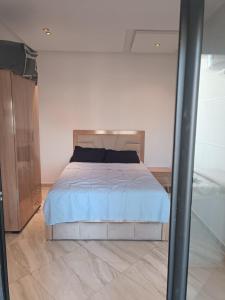a bedroom with a bed with a blue comforter at Mehdia Beach Apartment in Kenitra