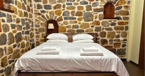 a bedroom with a bed in a stone wall at Palatino Seafront Residence in Alinda