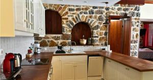 a kitchen with white cabinets and a stone wall at Palatino Seafront Residence in Alinda