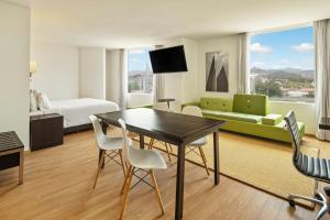 ein Hotelzimmer mit Tisch, Stühlen und Sofa in der Unterkunft Fiesta Inn Express Naucalpan in Mexiko-Stadt