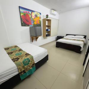 a room with two beds and a painting on the wall at Hotel Habitaciones D y Mar in Tolú