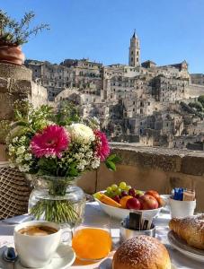 a table with a vase of flowers and coffee and food at Corte dei Venti in Matera