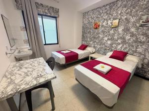 a hotel room with two beds and a sink at Evans Realty - Hostal in Fuengirola