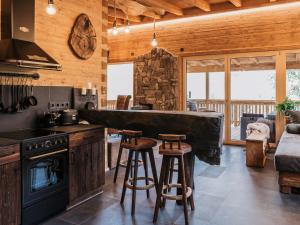 Eine Küche mit Herd und eine Bar mit Hockern in der Unterkunft Romantikchalet Fuchsbau mit eigenen Wellnessbereich, Komfort und viel Ruhe in der Natur in Vorra