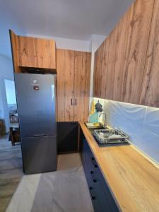 a kitchen with a stainless steel refrigerator and wooden cabinets at apartman Dalas Star Dojran in Star Dojran