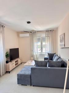 ein Wohnzimmer mit einer blauen Couch und einem Fernseher in der Unterkunft Elea residence in Elaiokhórion