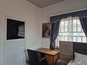 a bedroom with a desk and a bed and a window at D-vine Apartments & Hotels in Benin City