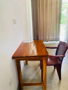 a wooden table and a chair next to a window at Kujaku in Arugam Bay