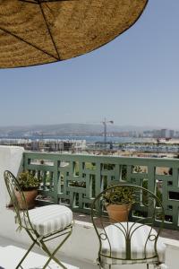 a patio with two chairs and a table and a balcony at Casa henione in Tangier