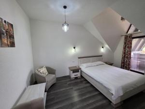 a bedroom with a white bed and a chair at Cabana OAZA AMURG in Runcu