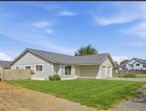 a large white house with a grass yard at Central Comfort Duplex in Moses Lake