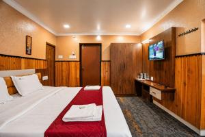 a hotel room with a large bed and a tv at Lake Residency Ooty in Ooty