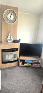 a room with a fireplace with a clock on the wall at South Breeze Caravans in Camber