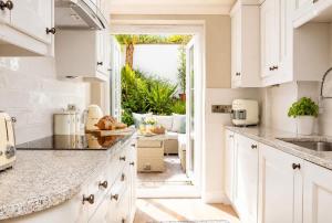 a kitchen with white cabinets and a large window at Crystal View by the Sea in Carbis Bay