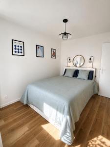a white bedroom with a large bed and wooden floors at Les Oyats in Équihen-Plage
