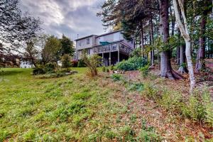 a large house on a grassy hill with trees at Dog-friendly 3-story home with wood stove, deck, grill, ocean views, W/D, AC in Southwest Harbor