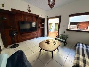 a living room with a table and a tv at Villavera - Caragua Centro in Caraguatatuba