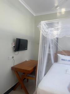 a bedroom with a bed with a wooden table and a tv at Angels Lodge in Dar es Salaam