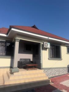 a small white house with a couch and a table at Angels Lodge in Dar es Salaam +3 photos