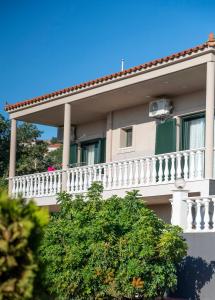 a white apartment building with a balcony and trees at Villa Twins in Myrina