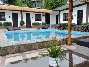 a pool with chairs and flowers in front of a house at V Hostel Galera in Puerto Galera
