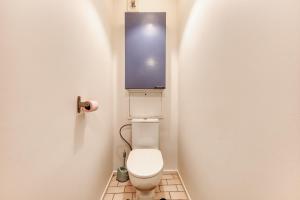 a bathroom with a toilet with a blue box on the wall at Charmant appartement proche Val Europe Disneyland paris in Torcy