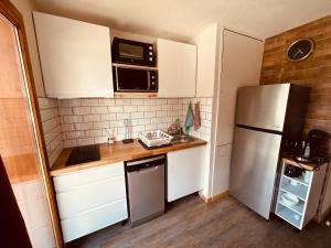 a small kitchen with white cabinets and a refrigerator at Le Chalet de Super D in Le Dévoluy