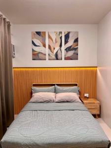 a bed in a bedroom with three paintings on the wall at Cozy Crib at Royal Oceancrest Mactan in Mactan Island +21 photos