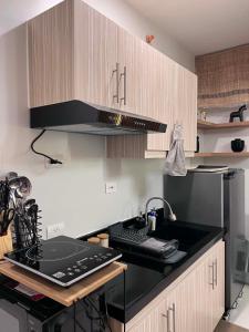 a kitchen with a black counter top and wooden cabinets at Cozy Crib at Royal Oceancrest Mactan in Mactan Island