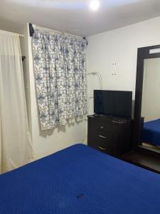 a bedroom with a blue bed and a television at Ruah Home in Guadalupe