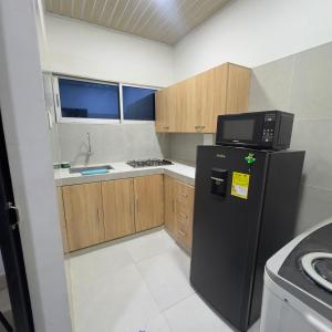 a kitchen with a black refrigerator and a microwave at Hotel Habitaciones D y Mar in Tolú +32 photos