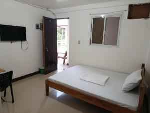 a bedroom with a bed and a tv in a room at V Hostel Galera in Puerto Galera