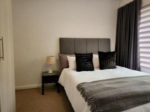 a bedroom with a large bed and a table with a lamp at Comfort & Style at the Ihita Complex - Beverley, Sandton in Sandton +22 photos
