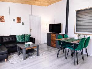 a living room with a table and green chairs at Dovolenkový dom in Mojš