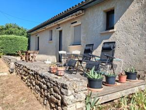 a stone retaining wall with chairs and potted plants at La borie de la croix in Daglan
