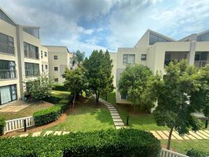 an apartment building with a garden in front of it at Comfort & Style at the Ihita Complex - Beverley, Sandton in Sandton