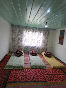 a room with three beds in a room with a window at Dosoi Guest House Experience Song-Kul with Horseback Tours in Kyzylemgek