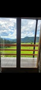 a window with a view of a field and a fence at Planinska kuća Vlašić in Vlasic +4 photos